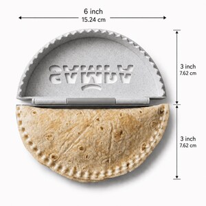 K&ouml;nnte beinhalten: Eine graue, gesprenkelte Kunststoff-Teigtaschenpresse mit dem ausgeschnittenen Wort SAMLA, 15,24 cm breit und 15,24 cm hoch, mit einer goldbraunen, gefalteten Tortilla in der unteren H&auml;lfte, die eine H&ouml;he von 7,62 cm aufweist.