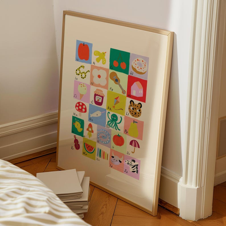 May include: A framed alphabet art print featuring colorful illustrations of various objects, each representing a letter. The artwork includes images of an apple, a flower, a guitar, a zebra, and more, set against a cream background.