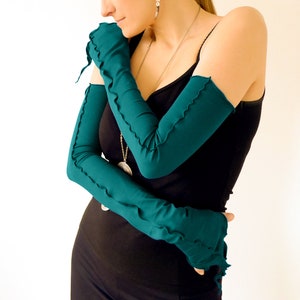 May include: Teal blue long fingerless gloves with a ruffled edge. The gloves are made of a soft, stretchy fabric.