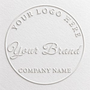 May include: A circular white embossed logo design on a textured paper surface. The text reads YOUR LOGO HERE in a circular arc at the top, Your Brand in a central script font, and COMPANY NAME in a straight line at the bottom of the circle.