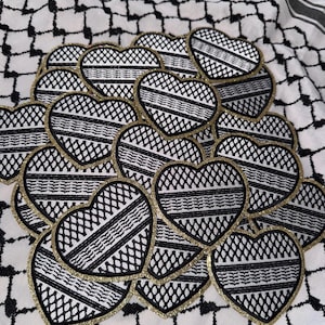 Puede incluir: Parches en forma de corazón con diseños geométricos en blanco y negro y bordes dorados con purpurina. Los parches están dispuestos sobre una tela a cuadros en blanco y negro, creando un contraste visual. Ideales para manualidades y proyectos creativos.