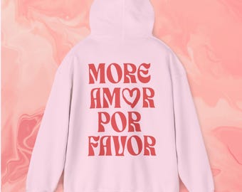 May include: Pink hoodie with a red graphic that says "MORE AMOR POR FAVOR" with a heart symbol in the word "AMOR".