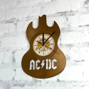 Könnte beinhalten: Eine weiße Keramik-Tasse mit schwarzem Henkel und dem Text "But First, Coffee" in fetter, schwarzer Schrift. Die Tasse steht vor einem verschwommenen Hintergrund, der eine gemütliche Umgebung andeutet.