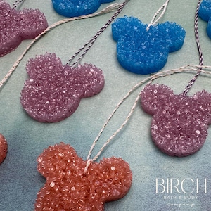 May include: Assortment of colorful, sparkly, Mickey Mouse-shaped car air fresheners with string hangers. The air fresheners are in shades of pink, blue, and orange.
