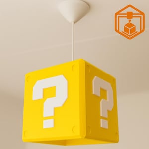 Könnte beinhalten: Gelbe, würfelförmige Hängeleuchte mit weißen Fragezeichen auf jeder Seite. Die Leuchte hängt an einer weißen Deckenhalterung. Das Design erinnert an ein Videospiel.