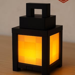 Può includere: Una lanterna nera a forma di cubo con una calda luce gialla. La lanterna ha una maniglia sulla parte superiore e un logo di stampa 3D. Il design è geometrico e moderno. Dimensioni in centimetri.
