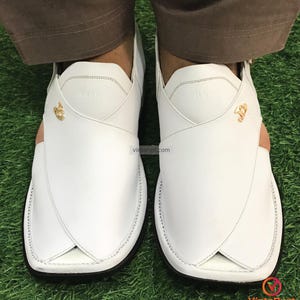 May include: White leather sandals with a gold buckle and stitching detail. The sandals have a pointed toe and a closed back.