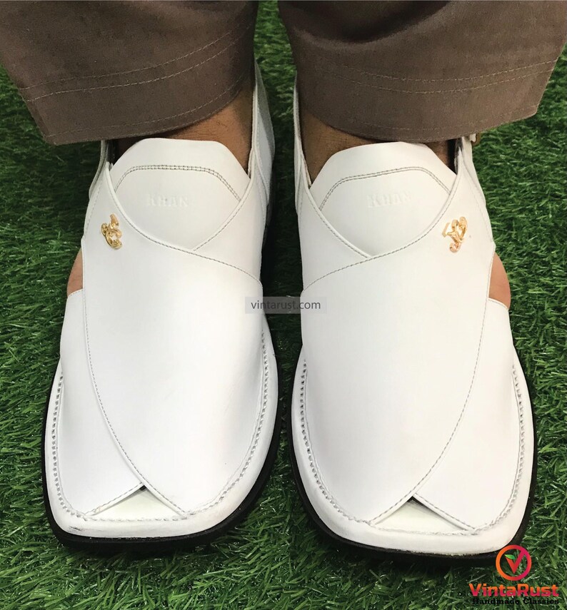 May include: White leather sandals with a gold buckle and stitching detail. The sandals have a pointed toe and a closed back.