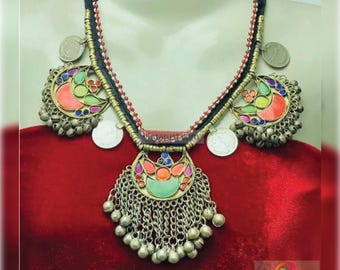 May include: A colorful, multi-layered necklace with silver coins, bells, and a crescent moon pendant. The pendant is decorated with colorful glass stones and has a chain of silver bells hanging from it.