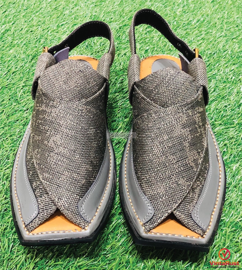 May include: A pair of gray leather sandals with a criss-cross strap design. The sandals have a pointed toe and a closed back.