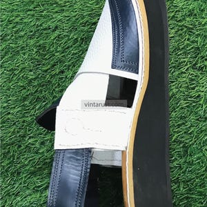 May include: White leather sandals with a blue leather strap and a black rubber sole. The sandals have a unique design with a cut-out detail on the top.
