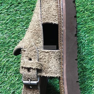 May include: A brown suede sandal with a buckle fastening and a brown leather sole. The sandal has a cut-out design on the top.