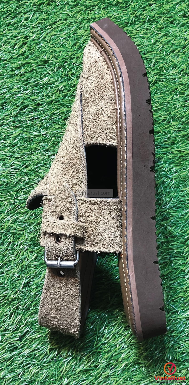 May include: A brown suede sandal with a buckle fastening and a brown leather sole. The sandal has a cut-out design on the top.