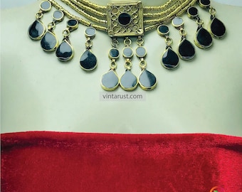 May include: A gold choker necklace with black glass teardrop pendants. The necklace has a square centerpiece with a black glass center and a gold filigree design.