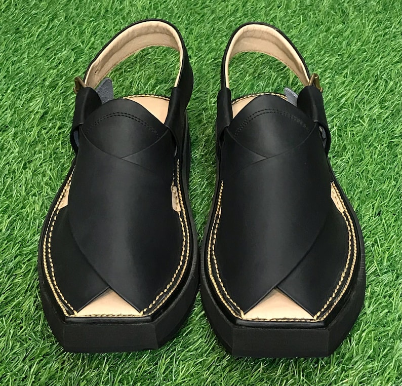 May include: A pair of black leather sandals with a closed toe and a strap across the top of the foot. The sandals have a gold stitching detail around the edges.