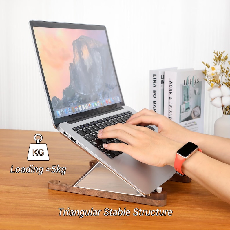 May include: A wooden laptop stand with a triangular stable structure. The stand is holding a silver laptop. The text on the image says "Loading &asymp;5kg" and "Triangular Stable Structure".