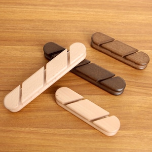 May include: Four wooden bread slicers in various shades of brown and natural wood. Each slicer has a unique design with a series of angled slots for guiding a knife. The items are arranged on a wooden surface.