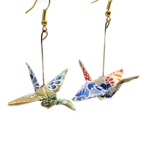 May include: A pair of gold origami crane earrings. The cranes are made of colorful patterned paper and are suspended from gold hooks.