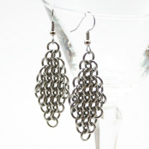 May include: A pair of silver chain earrings with a diamond shape. The earrings are made of small, interconnected metal links.