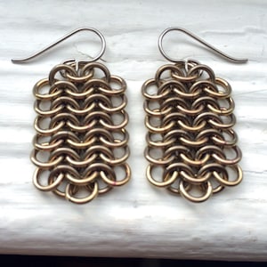 May include: A pair of gold chainmail earrings with silver hooks.