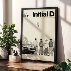 May include: A framed poster featuring the text Initial D at the top, with a graphic illustration of four individuals standing in a line next to a white car. The background is a light cream color with Japanese text printed vertically in the center.