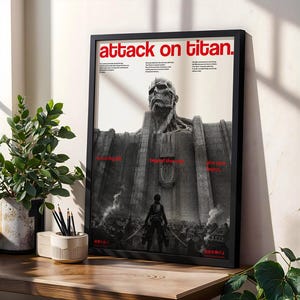 Pode incluir: Um cartaz vertical emoldurado intitulado Attack on Titan com uma ilustração a preto e branco de uma cabeça de titã colossal a espreitar por cima de uma parede de pedra maciça. Uma pequena figura está em primeiro plano virada para a parede.