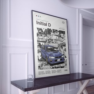 Könnte beinhalten: Ein schwarz-weißes Poster mit einem blauen Auto in der Mitte. Das Poster trägt den Titel "Initial D" und oben den Text "Studio Comet Production". Das Poster enthält auch das Jahr "1998" und eine Namensliste.