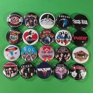 Puede incluir: Una colección de veintiún botones redondos con logotipos de bandas y portadas de álbumes. Los botones son de varios colores, incluyendo negro, blanco, rojo y azul. Las bandas incluyen Cheap Trick, Journey y Heart.