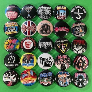 Pode incluir: Uma coleção de 28 botões redondos com várias bandas de rock, incluindo Queen, Rush e AC/DC. Os botões são pretos, brancos e coloridos, com logotipos de bandas e arte de álbuns. Os botões estão dispostos em uma superfície verde.