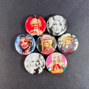 Puede incluir: Seis chapas redondas con diversos retratos fotográficos de Dolly Parton. Los diseños incluyen imágenes en color y en blanco y negro, con una chapa que muestra el texto Dolly Parton y otra que presenta el texto Saint Dolly.