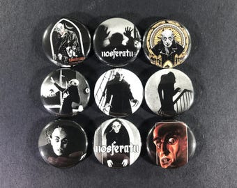 May include: Nine round black and white buttons featuring images of the vampire Nosferatu. The buttons have various images of the vampire, including his face, silhouette, and scenes from the movie.