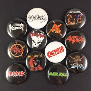 Può includere: Una collezione di spille rotonde di gruppi metal in bianco e nero. Le spille presentano loghi e immagini di band, tra cui "Metallica", "Slayer" e "Megadeth". Le spille rotonde hanno una finitura lucida, adatte per giacche o borse.