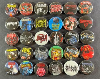 Op de afbeelding: Een verzameling van 30 ronde metalen pinback-buttons met logo's en artwork van verschillende heavy metal bands. De buttons hebben een verscheidenheid aan kleuren, waaronder rood, zwart, wit en blauw, en zijn gerangschikt in een rasterpatroon.