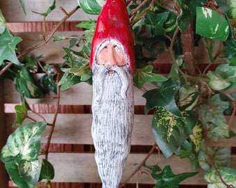 May include: A handmade Christmas ornament shaped like a gnome with a red hat, white beard, and a painted face.