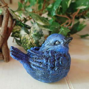 May include: A blue bird figurine with a textured finish. The bird is sitting on a white surface.