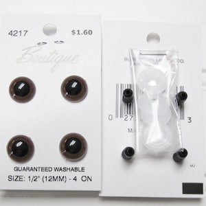 May include: Four brown plastic safety eyes with black pupils, measuring 1/2 inch (12 mm) in diameter. The eyes are packaged on a white card with the text "4217", "Boutique", "$1.60", "GUARANTEED WASHABLE", and "SIZE: 1/2" (12MM) - 4 ON".