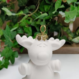 May include: White ceramic moose ornament with a gold-colored metal hanger. The moose is sitting with its legs tucked under its body.