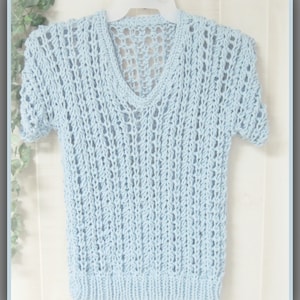 May include: A light blue knitted sweater with a V-neck and short sleeves. The sweater has an openwork design.