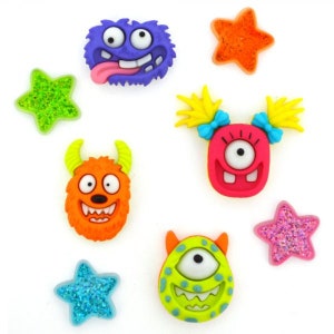May include: A collection of colorful monster and star-shaped embellishments. The monsters are in various colors, including purple, orange, and green, with expressive faces. The stars are glittery in shades of green, orange, blue, and pink.