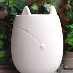 May include: White ceramic planter shaped like a fox with a simple face design. The planter has four legs and a wide opening for planting.
