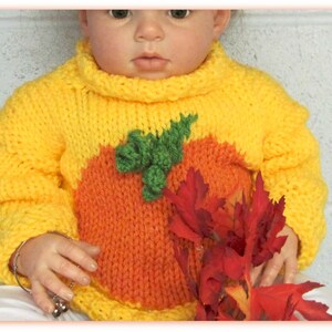 K&ouml;nnte beinhalten: Ein gelber Strickpullover mit einem orangefarbenen K&uuml;rbisdesign und gr&uuml;nen Bl&auml;ttern. Der Pullover hat einen Rollkragen und lange &Auml;rmel.