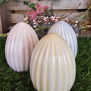 May include: Three ceramic Easter eggs with a striped design. The eggs are in shades of pink, yellow, and blue.