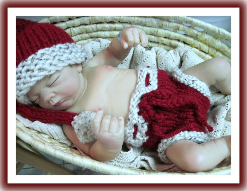 May include: A red and white knitted hat and diaper set for a baby. The hat has a long, pointed tip and a white brim. The diaper has a white trim and a red center.