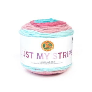 May include: A ball of Lion Brand Just My Stripe yarn in a pink and blue color combination. The label reads "Lion Brand Yarns Just My Stripe" and includes the website address LionBrand.com. The label also states "Over 8000 free patterns! Plus de 8000 gabarits gratuits!"