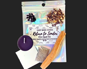 May include: A mini spell kit in a holographic pouch labeled Easy Bake Coven Return to Sender Mini Spell Kit. The kit includes a purple tea light candle, a small bag of brown salt, a pile of dark stones, dried herbs, and a wooden stick.