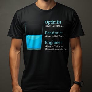 May include: Black t-shirt featuring a graphic of a glass half full of blue liquid. Text reads: Optimist, Pessimist, and Engineer, each with a different perspective on the glass. The shirt is worn by a person.