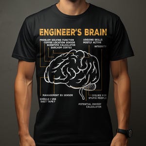 Op de afbeelding: Zwart T-shirt met een witte afbeelding van een hersen met het opschrift "Engineer's Brain". De afbeelding bevat tekst over probleemoplossing, sarcasme en andere engineering-gerelateerde functies. Het T-shirt wordt door een persoon gedragen.