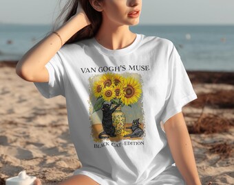May include: White t-shirt featuring a graphic of sunflowers in a vase with two black cats. The text on the shirt reads "Van Gogh's Muse" and "Black Cat Edition". The design is a whimsical take on a classic painting.