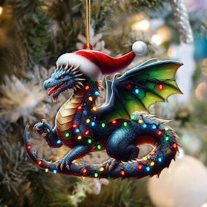May include: A Christmas ornament featuring a blue dragon wearing a Santa hat and adorned with colorful string lights. The dragon has green and yellow wings and a red tongue. The ornament is hanging from a gold string.