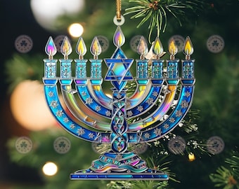 May include: A Hanukkah menorah ornament with a stained glass appearance. The blue and iridescent menorah features nine candle holders with flames, a Star of David, and decorative details. It hangs from a gold cord against a blurred background of a Christmas tree.